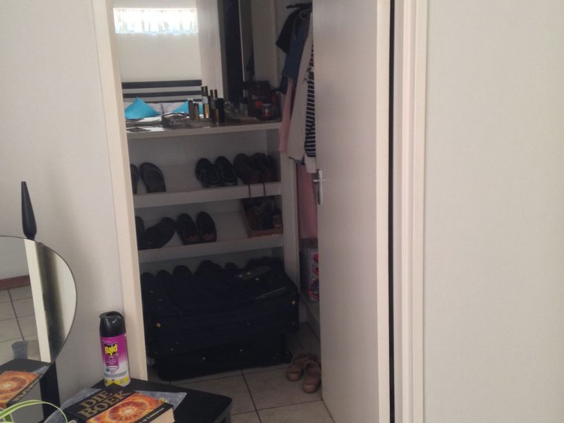 A view into a walk-in closet or utility storage space featuring built-in shelving and tiled flooring.