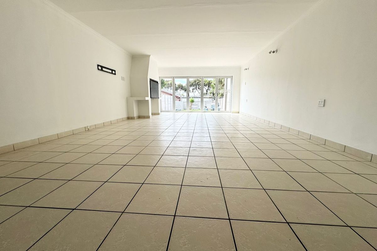 A spacious, empty living room featuring tiled flooring, a built-in fireplace, and large sliding glass doors providing natural light and access to the outdoors.