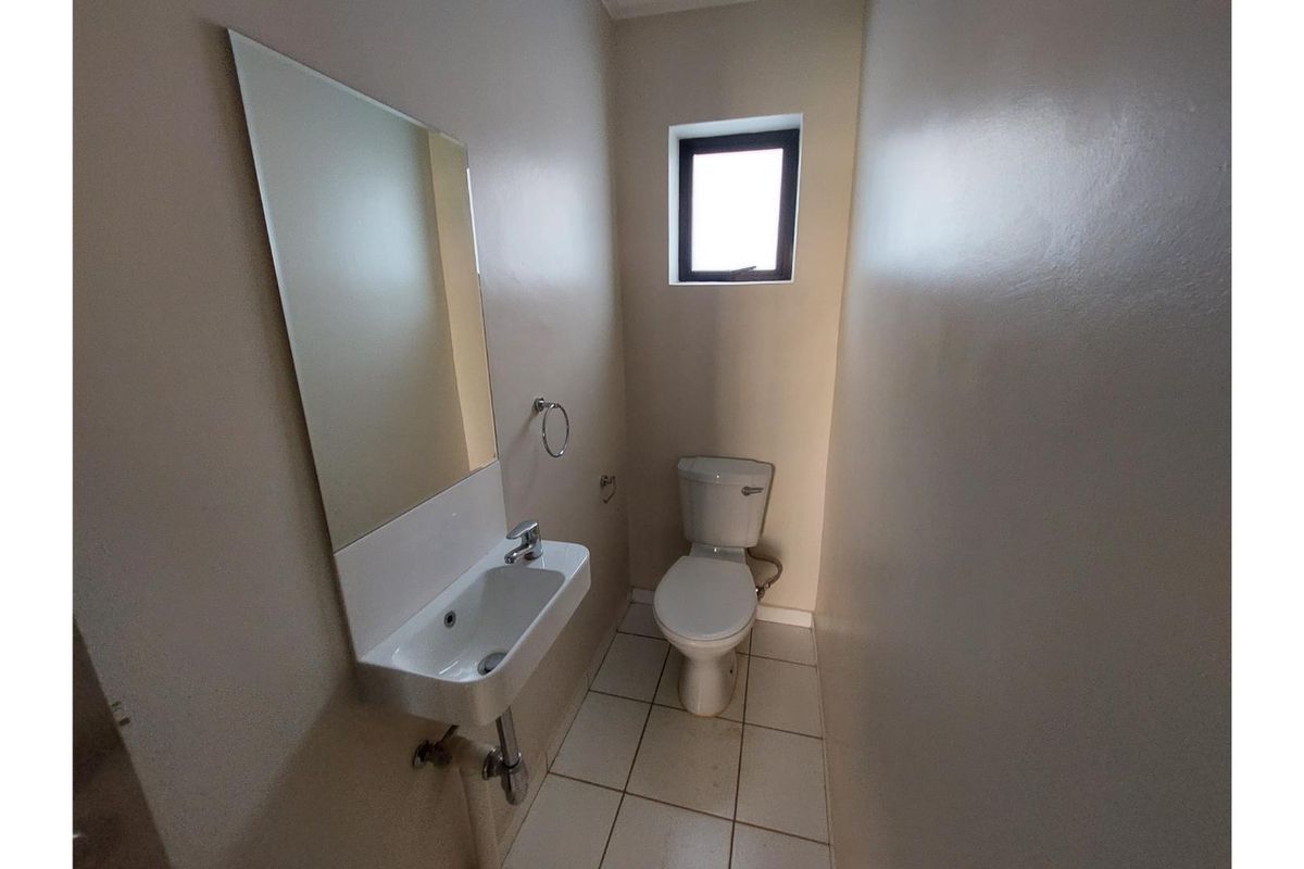A compact guest bathroom featuring a wall-mounted basin, toilet, and tiled flooring, providing a functional and minimalist space.