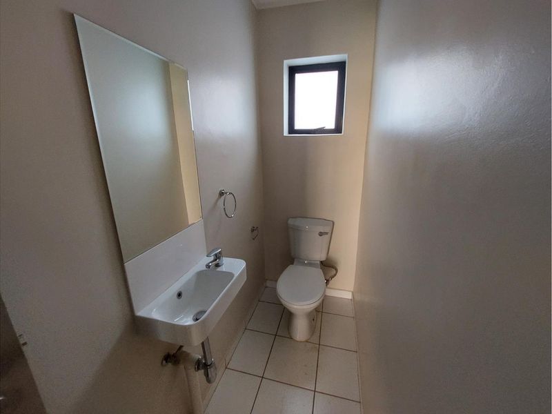 A compact guest bathroom featuring a wall-mounted basin, toilet, and tiled flooring, providing a functional and minimalist space.