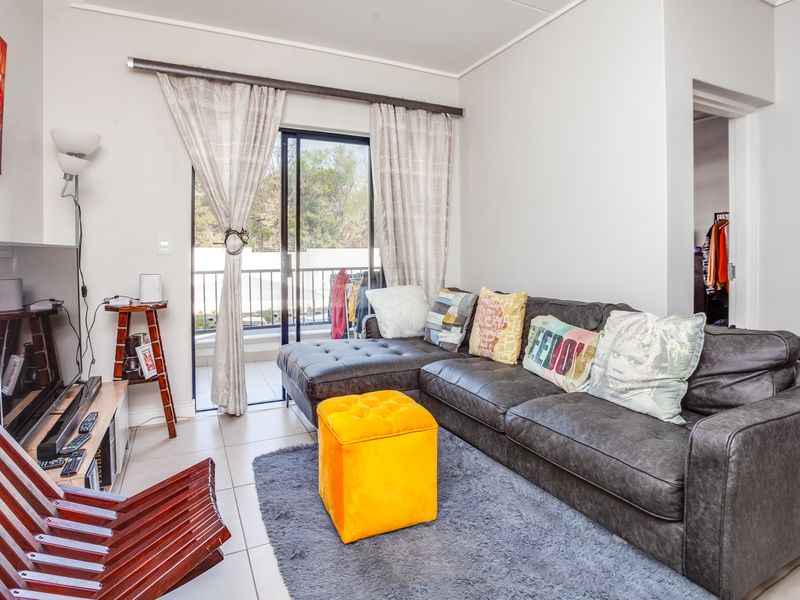 A living room featuring tiled flooring and a sliding glass door providing access to an outdoor balcony area.