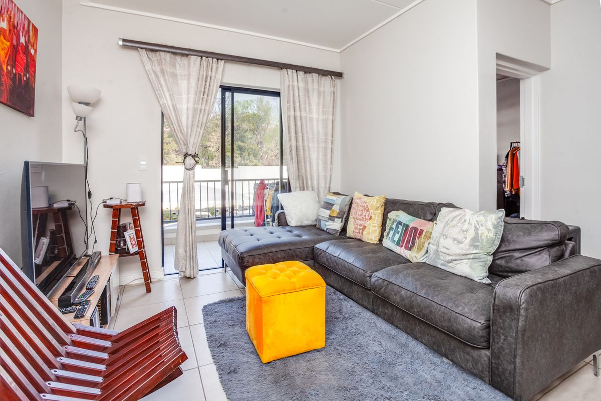 A living room featuring tiled flooring and a sliding glass door providing access to an outdoor balcony area.