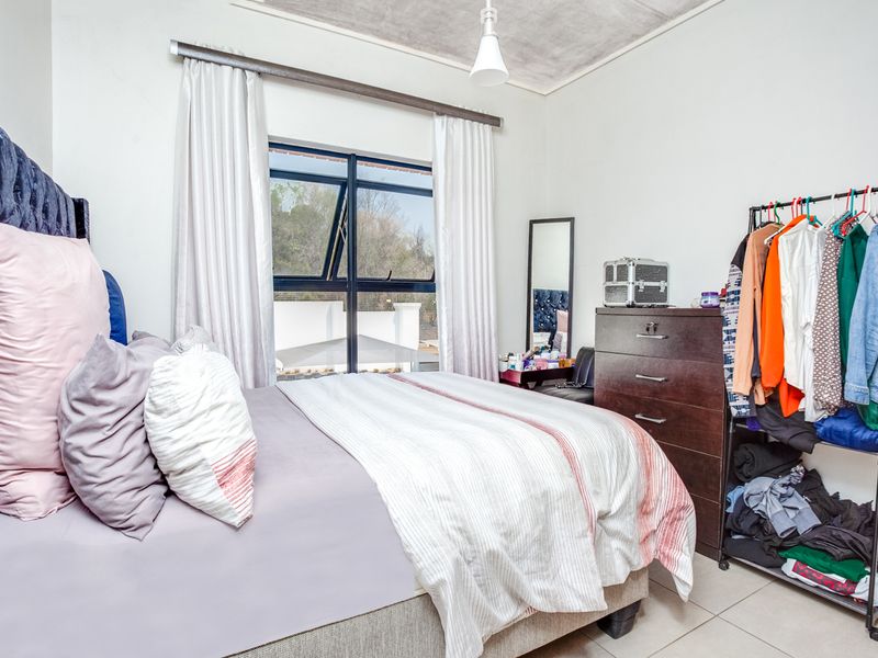 A standard bedroom featuring tiled flooring, a large aluminium-framed window, and a ceiling light fixture.