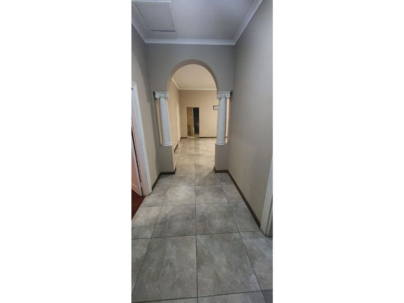 A spacious hallway featuring tiled flooring and a decorative archway supported by classical columns, leading through to the interior living spaces.