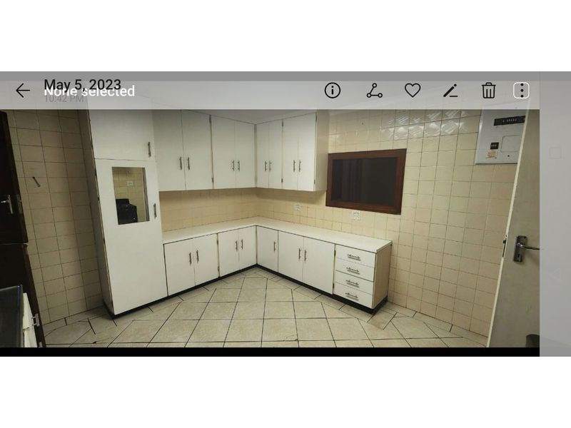 A dated, empty kitchen featuring white built-in cabinetry, tiled walls, and tiled flooring, suitable for a modern renovation.