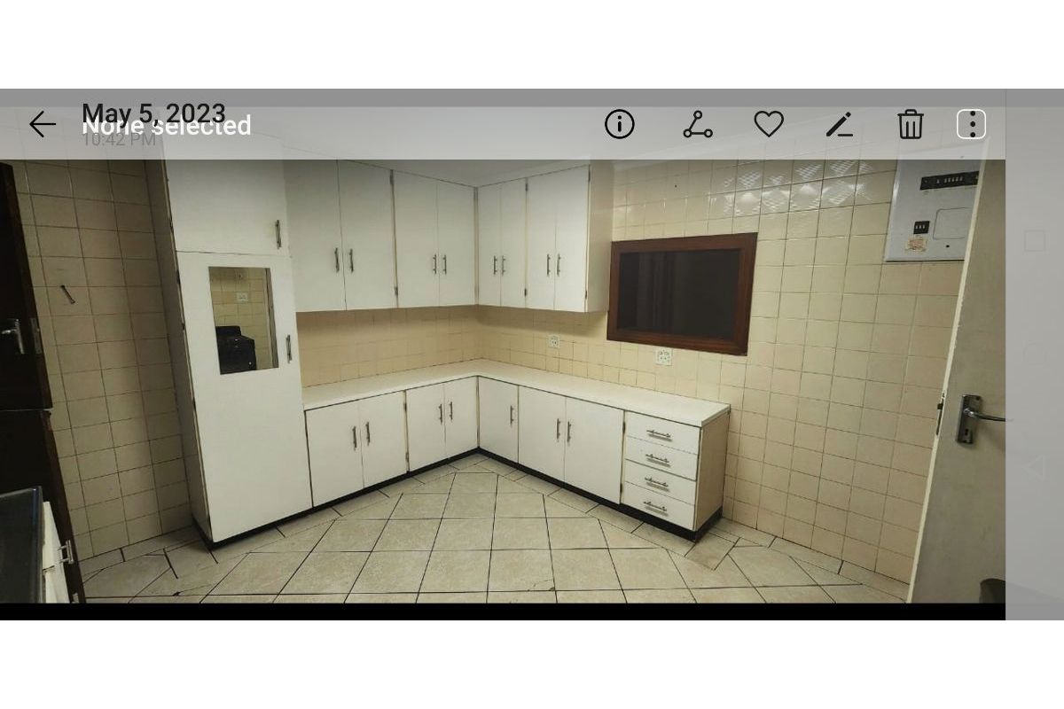 A dated, empty kitchen featuring white built-in cabinetry, tiled walls, and tiled flooring, suitable for a modern renovation.