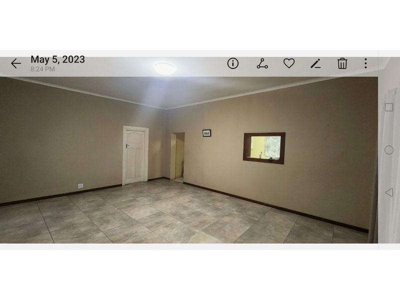 An empty living room featuring neutral wall paint, tiled flooring, and an internal service window connecting to an adjacent space.