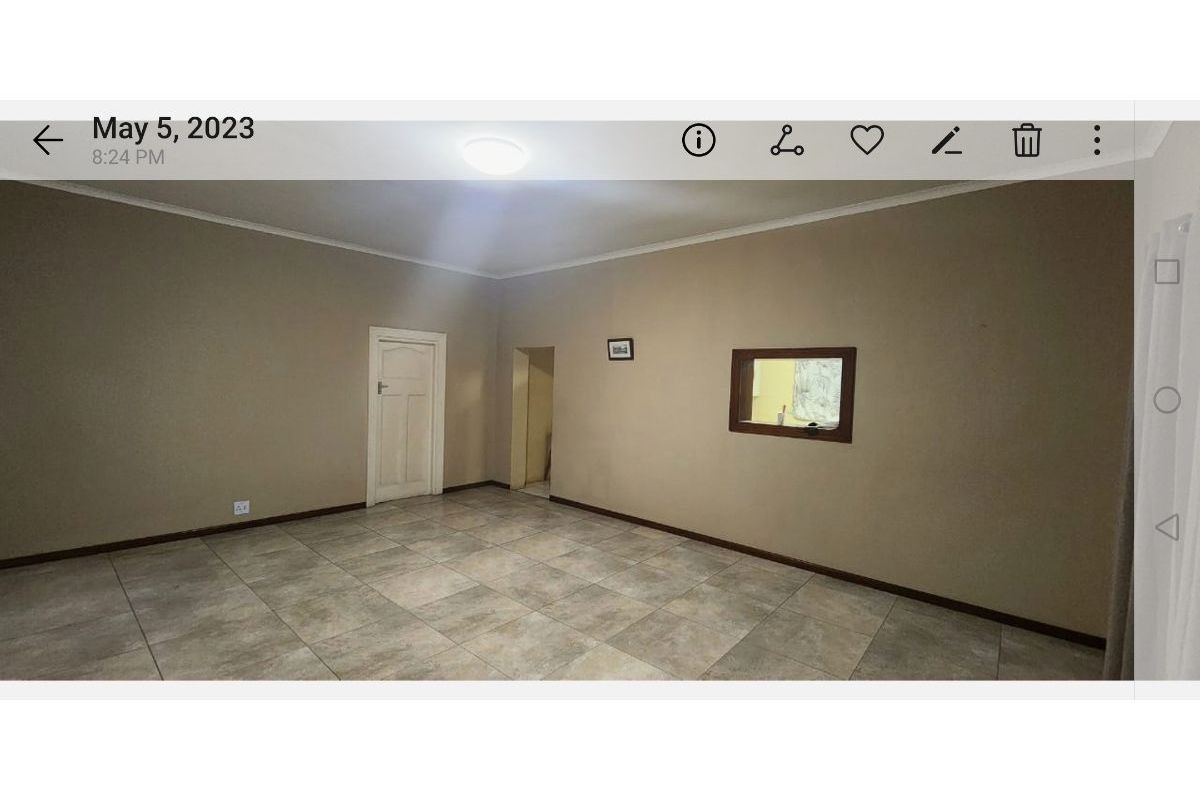 An empty living room featuring neutral wall paint, tiled flooring, and an internal service window connecting to an adjacent space.