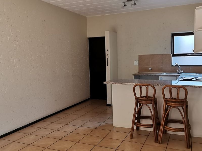 Open plan kitchen and living area featuring tiled flooring, granite countertops, and a built-in hob, offering a functional blank canvas for renovation.