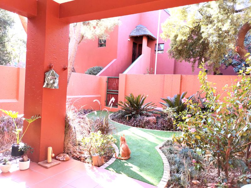 A covered patio area overlooking a private landscaped garden with a boundary wall and established greenery.