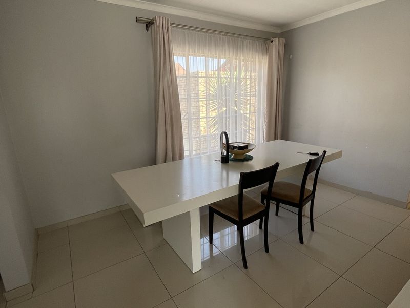 A simple dining area featuring neutral tiled flooring and a coved ceiling, providing a clean and functional space for meals.