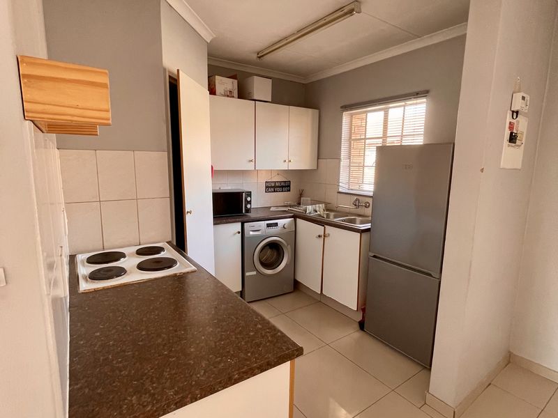 Compact kitchen featuring built-in cabinetry, laminate countertops, an electric hob, and tiled flooring, offering a functional layout for daily meal preparation.