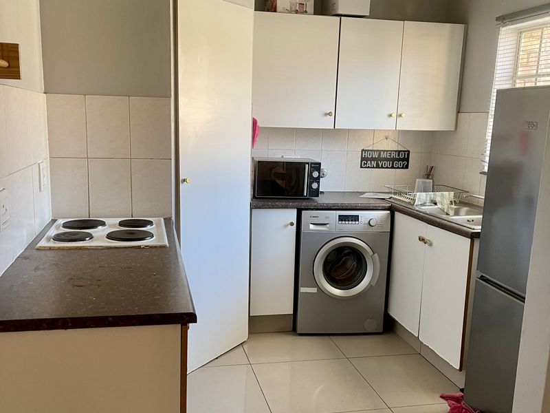 Compact kitchen featuring tiled flooring, laminate countertops, built-in cabinetry, and a tiled splashback with an integrated electric hob.