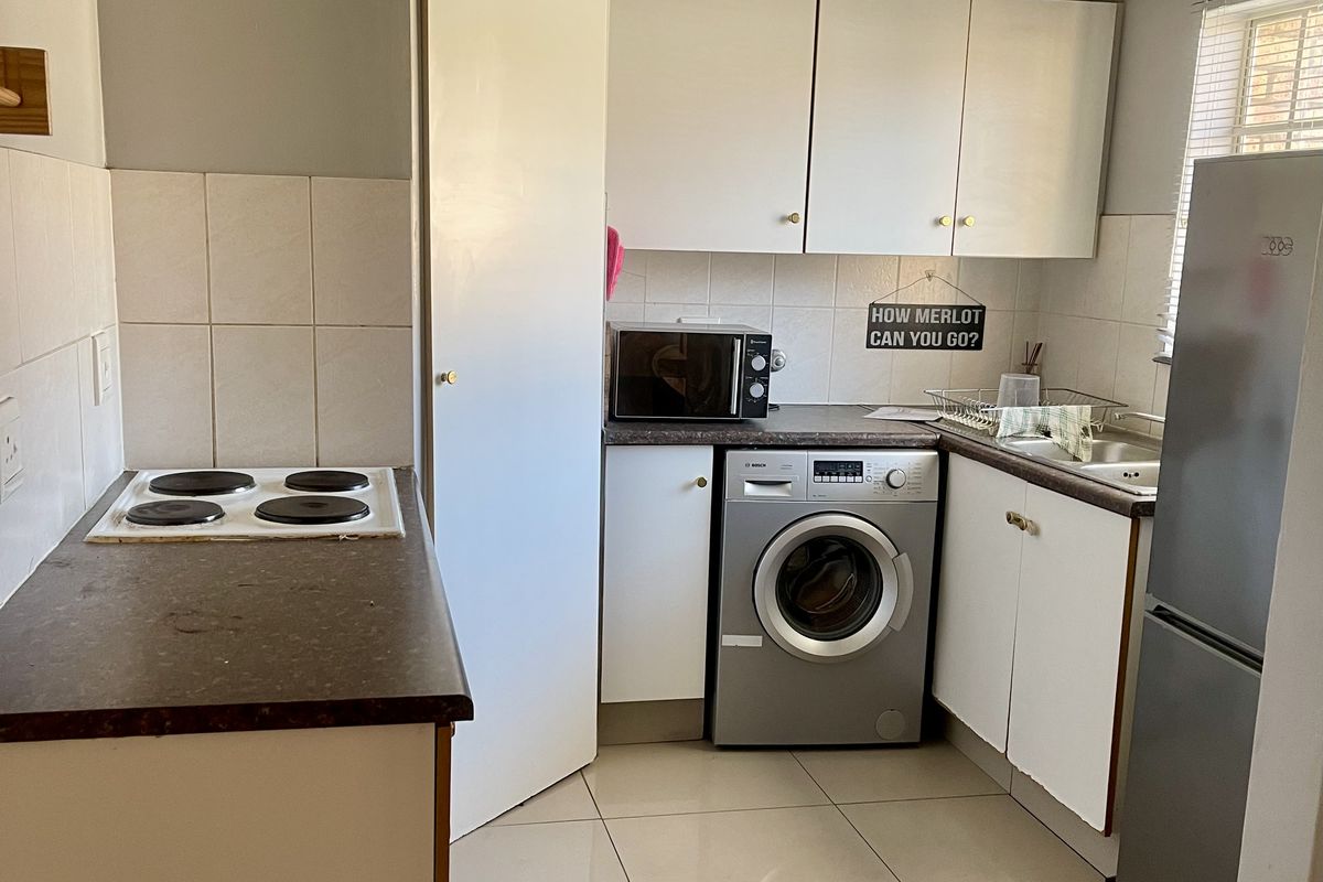Compact kitchen featuring tiled flooring, laminate countertops, built-in cabinetry, and a tiled splashback with an integrated electric hob.