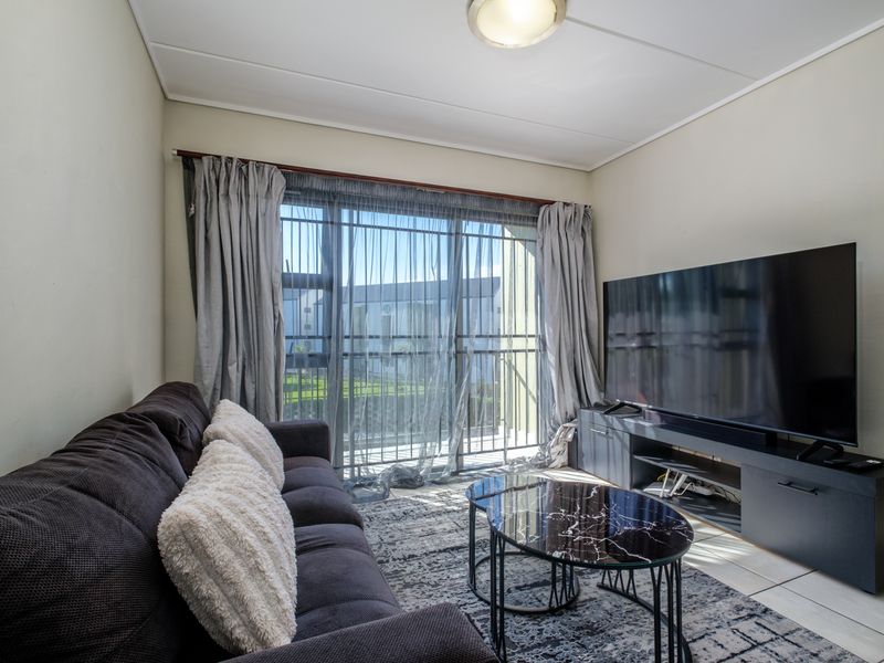 A comfortable living room featuring tiled flooring and a large sliding glass door that provides access to an outdoor balcony area.