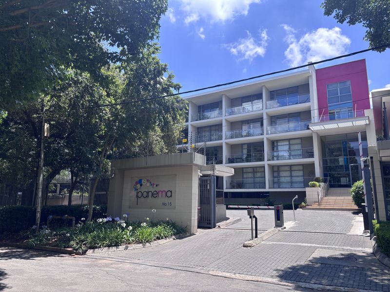 Front exterior view of the Ipanema apartment complex, featuring a secure gated entrance, paved driveway, and multi-level building facade with private balconies.