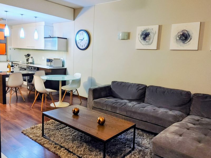 A modern open-plan living and kitchen area featuring laminate flooring, contemporary cabinetry, and integrated appliances, creating a functional and cohesive living space.