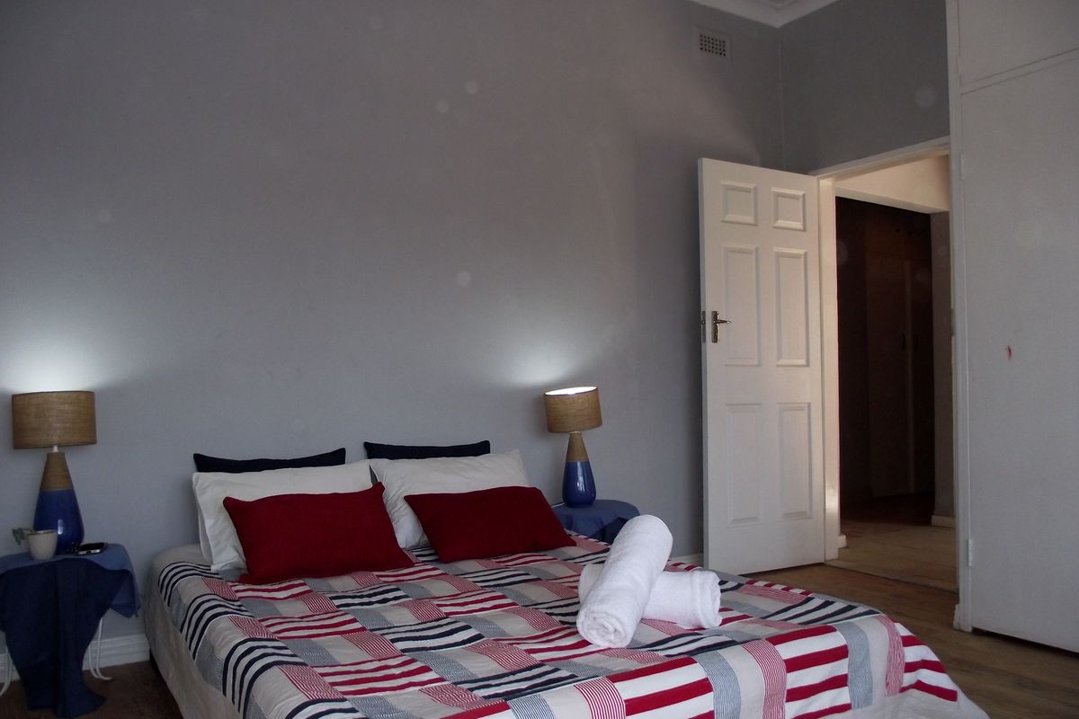 A bedroom featuring timber flooring, neutral wall finishes, and a built-in cupboard, providing a functional and well-lit sleeping space.