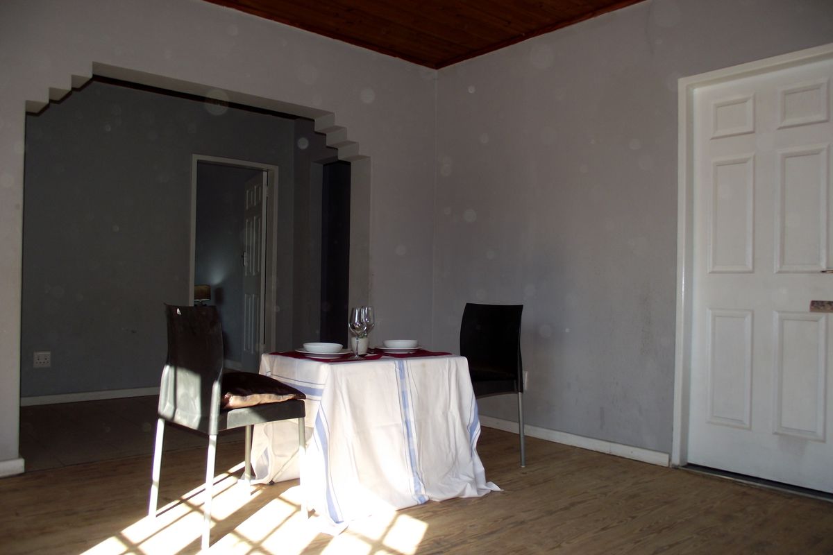 A living area featuring laminate flooring, a timber ceiling, and a distinctive stepped archway leading to an adjacent room.