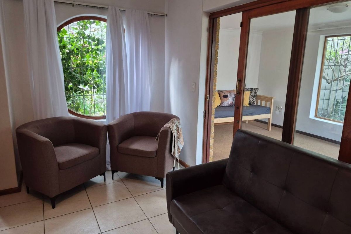 A living area featuring tiled flooring, a distinctive circular window with security bars, and wooden sliding doors leading to an adjacent room.