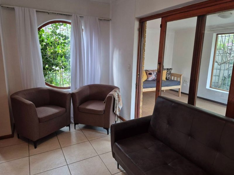 A living area featuring tiled flooring, a distinctive circular window with security bars, and wooden sliding doors leading to an adjacent room.