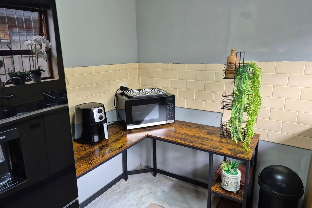 A functional kitchen corner featuring subway tile backsplash, wood-look laminate countertops, and a metal frame structure.