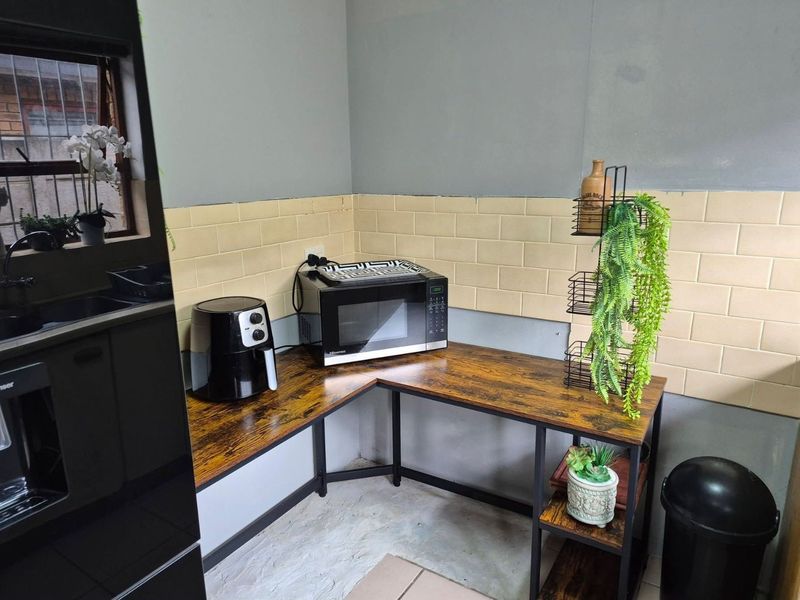 A functional kitchen corner featuring subway tile backsplash, wood-look laminate countertops, and a metal frame structure.