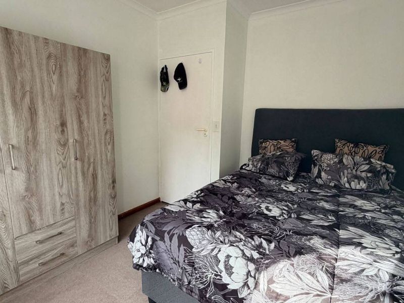 A bedroom featuring neutral carpeting and a built-in wood-grain wardrobe with integrated storage.