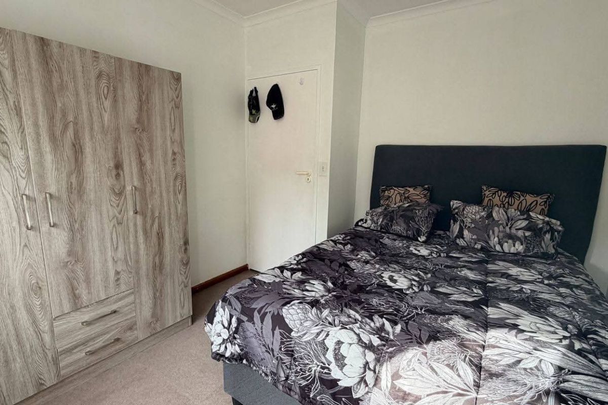 A bedroom featuring neutral carpeting and a built-in wood-grain wardrobe with integrated storage.