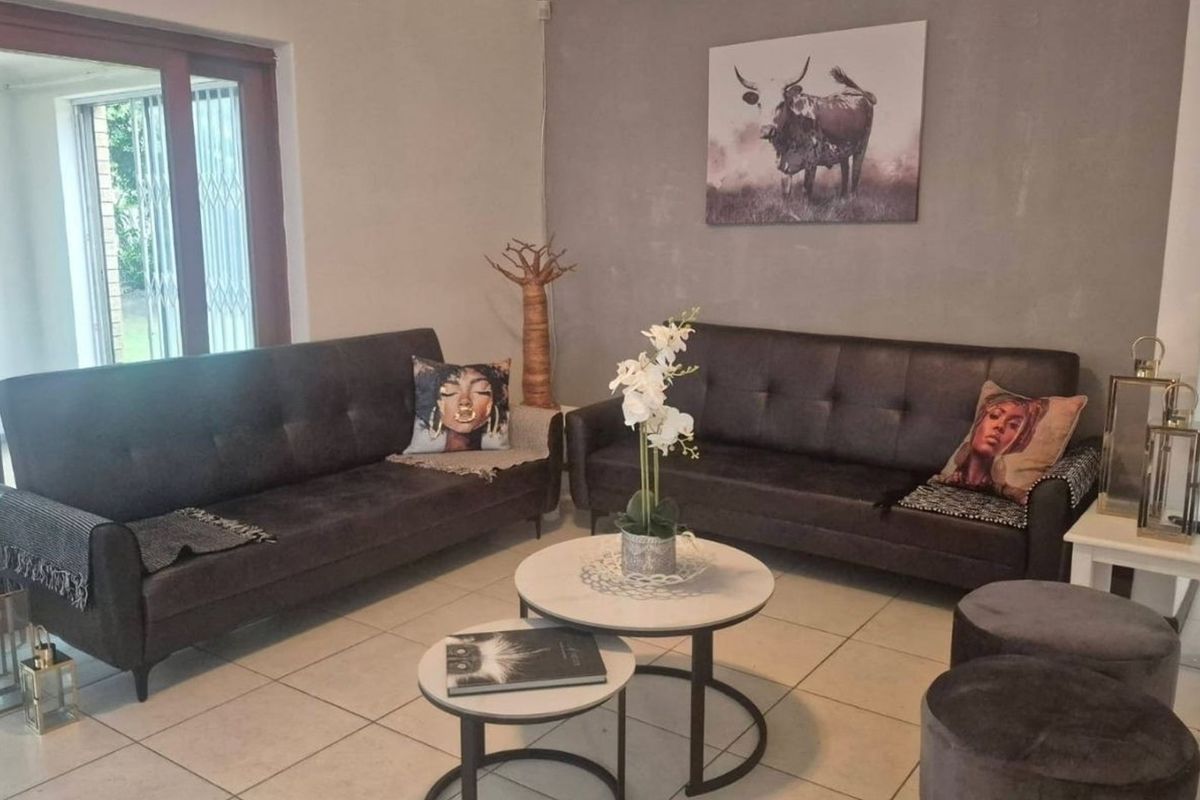 A living room featuring tiled flooring and a sliding glass door with a security gate, providing access to the outdoor area.