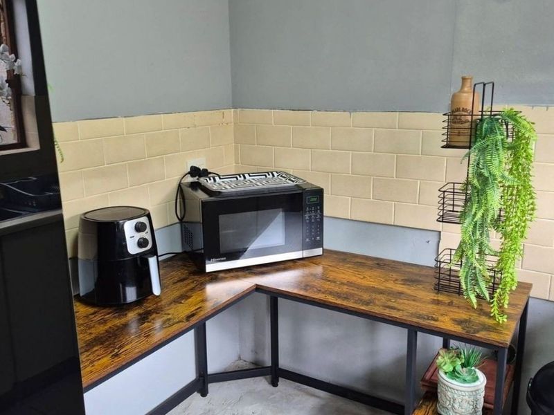 A kitchen corner featuring a light-colored subway tile backsplash and a wood-look laminate countertop workspace.