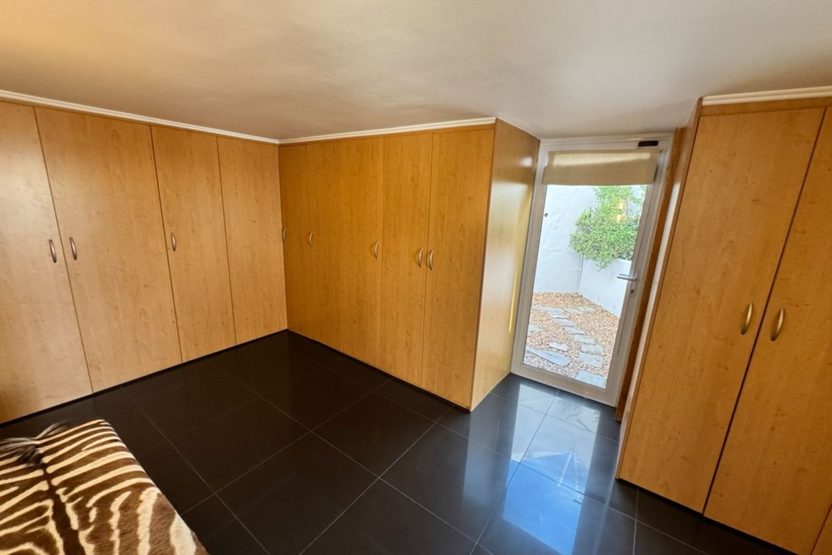 Bedroom featuring extensive built-in wooden cabinetry, dark tiled flooring, and a glass door providing direct access to a small outdoor courtyard area.