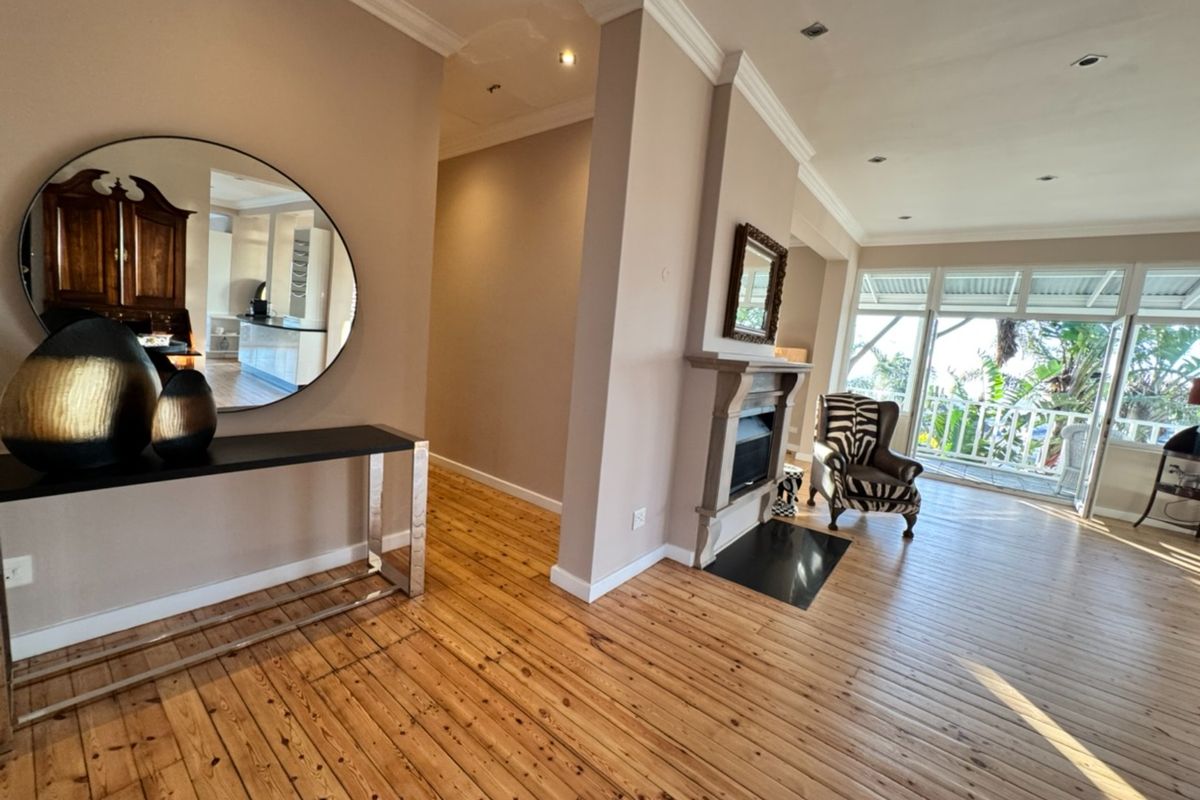 Spacious living area featuring polished timber flooring, a built-in fireplace, and seamless access to an outdoor balcony.