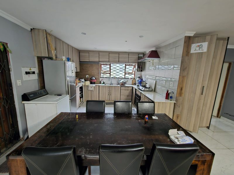 Open-plan kitchen and dining area featuring wood-look cabinetry, built-in appliances, and tiled splashbacks, providing a functional space for cooking and family meals.
