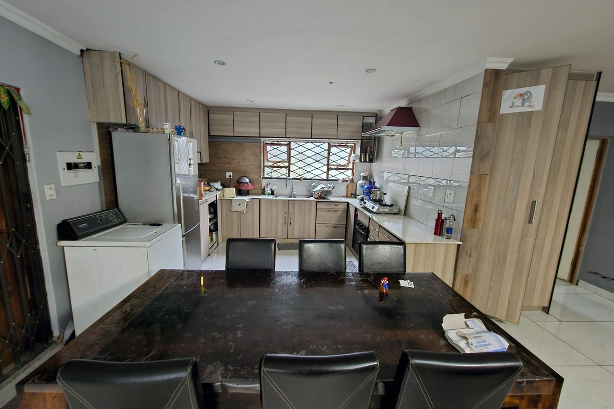 Open-plan kitchen and dining area featuring wood-look cabinetry, built-in appliances, and tiled splashbacks, providing a functional space for cooking and family meals.