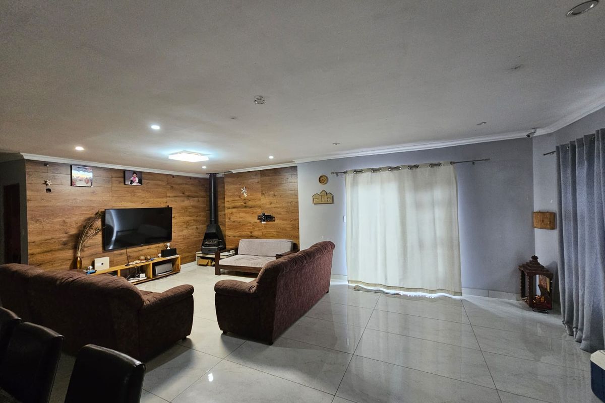 Spacious living room featuring wood-look accent wall paneling, a freestanding fireplace, large format floor tiles, and direct access to the outdoors via sliding doors.