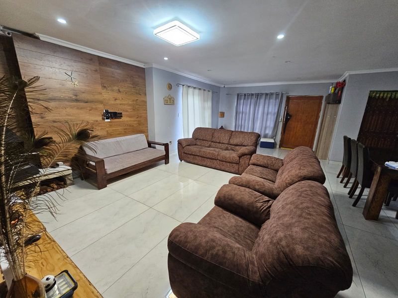 Spacious living room featuring a wood-look accent wall, tiled flooring, recessed lighting, and a built-in fireplace, offering a comfortable and functional layout.