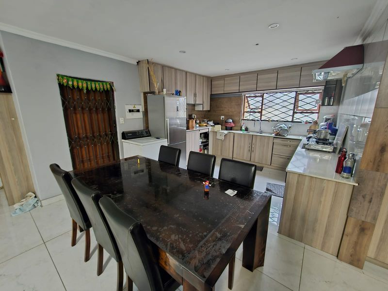 Open-plan kitchen and dining area featuring modern wood-look cabinetry, tiled flooring, and integrated kitchen fixtures, providing a functional and connected living space.