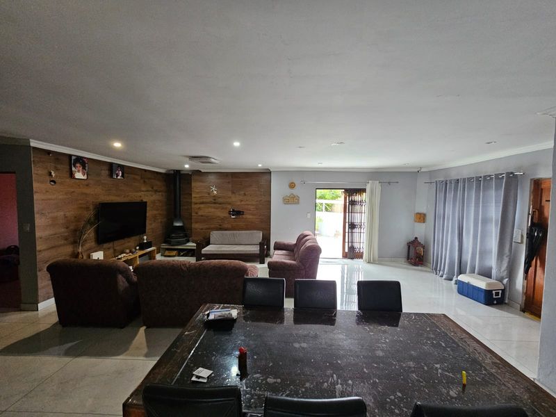Spacious open-plan living and dining area featuring a wood-look accent wall, a freestanding fireplace, and large sliding doors leading to the exterior.