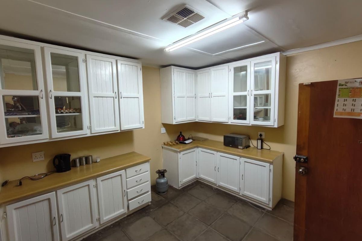 A functional kitchen featuring white cabinetry, laminate countertops, and tiled flooring, offering a practical layout with ample storage space.