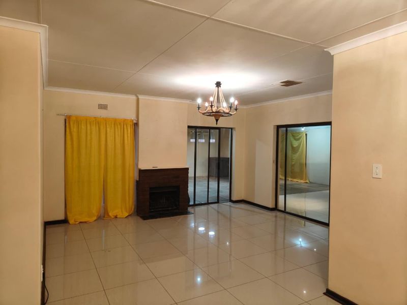 Spacious living room featuring tiled flooring, a built-in fireplace, and sliding glass doors leading to an adjacent area.