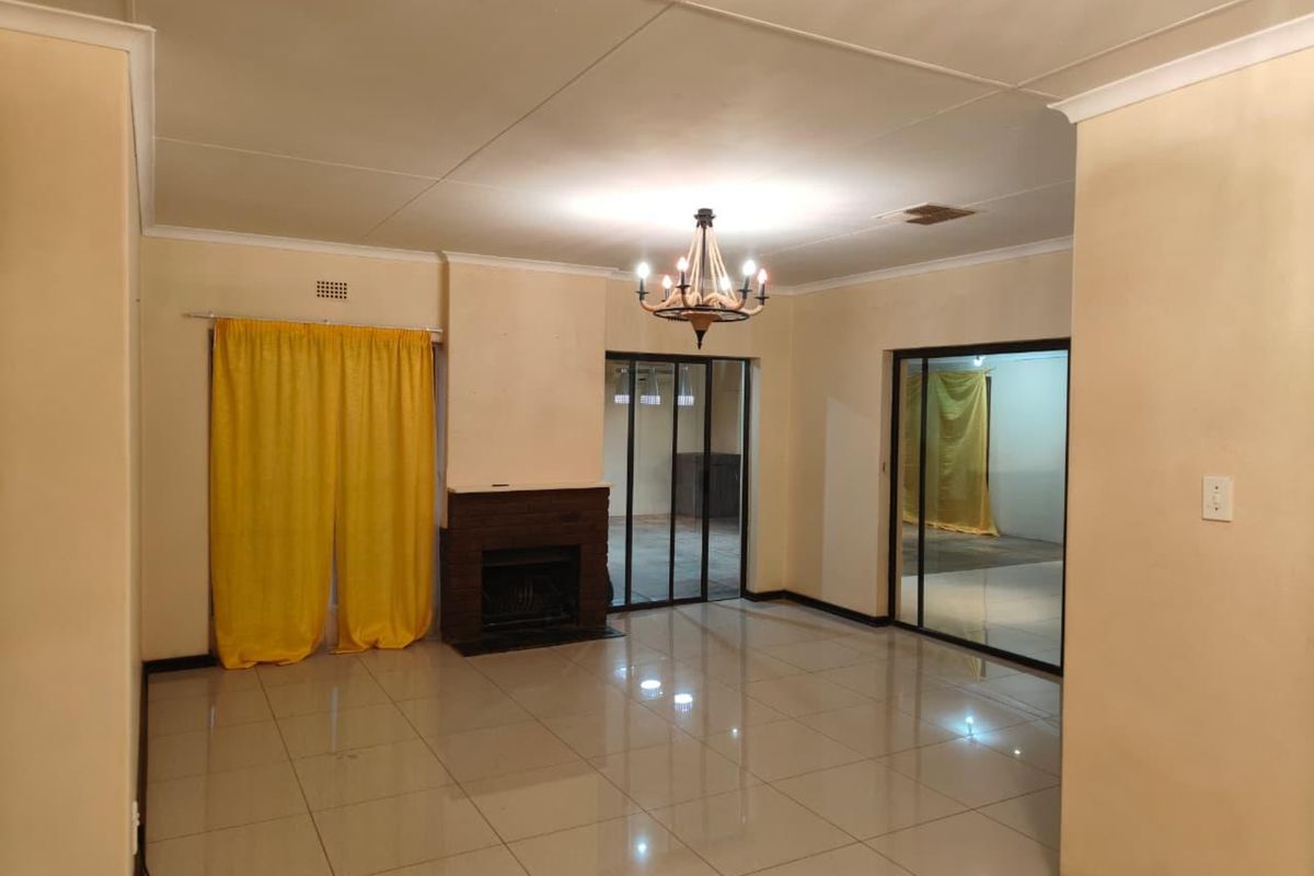 Spacious living room featuring tiled flooring, a built-in fireplace, and sliding glass doors leading to an adjacent area.