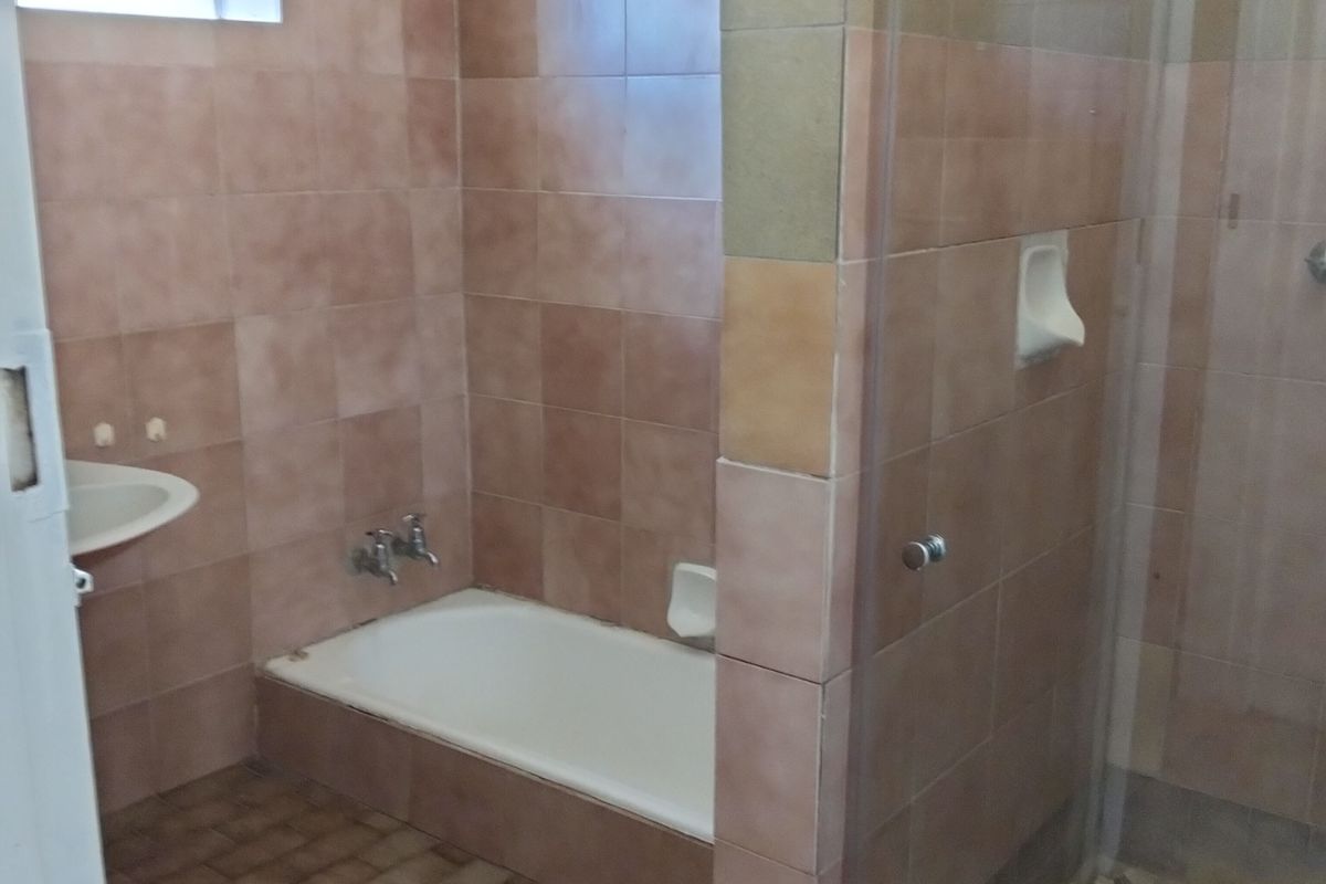 A dated bathroom featuring a built-in bathtub, a separate glass-enclosed shower, and wall-to-wall tiling throughout.