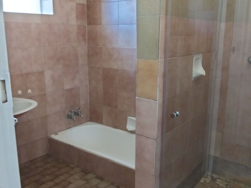 A dated bathroom featuring a built-in bathtub, a separate glass-enclosed shower, and wall-to-wall tiling throughout.