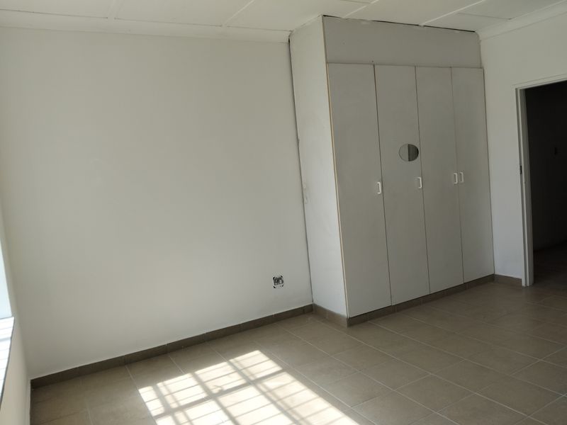 A vacant bedroom featuring neutral floor tiles and built-in storage cupboards with integrated mirror detail.