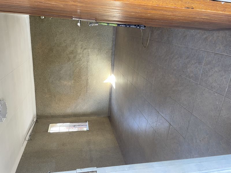 An empty, neutrally finished room featuring tiled flooring and textured walls, offering a blank canvas for potential living or office space.
