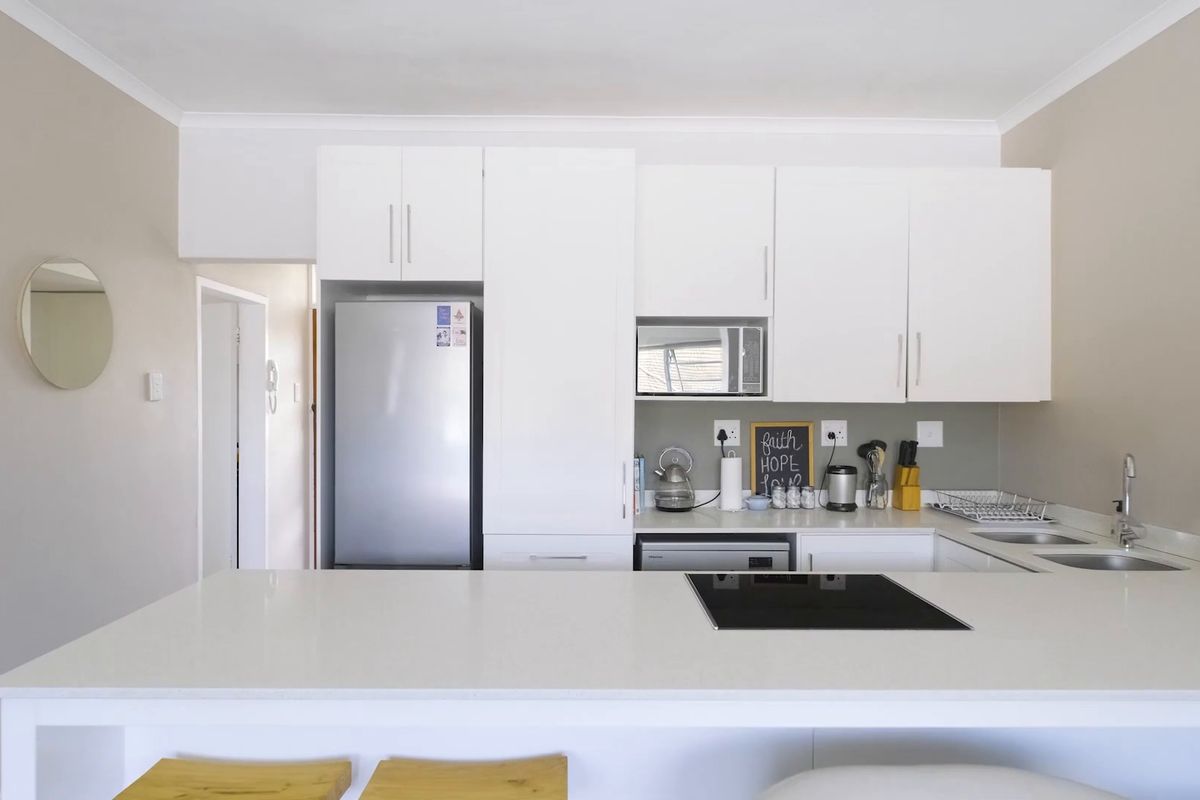 Modern kitchen featuring white cabinetry, stone countertops, a built-in induction hob, and a stainless steel sink, offering a clean and functional workspace.