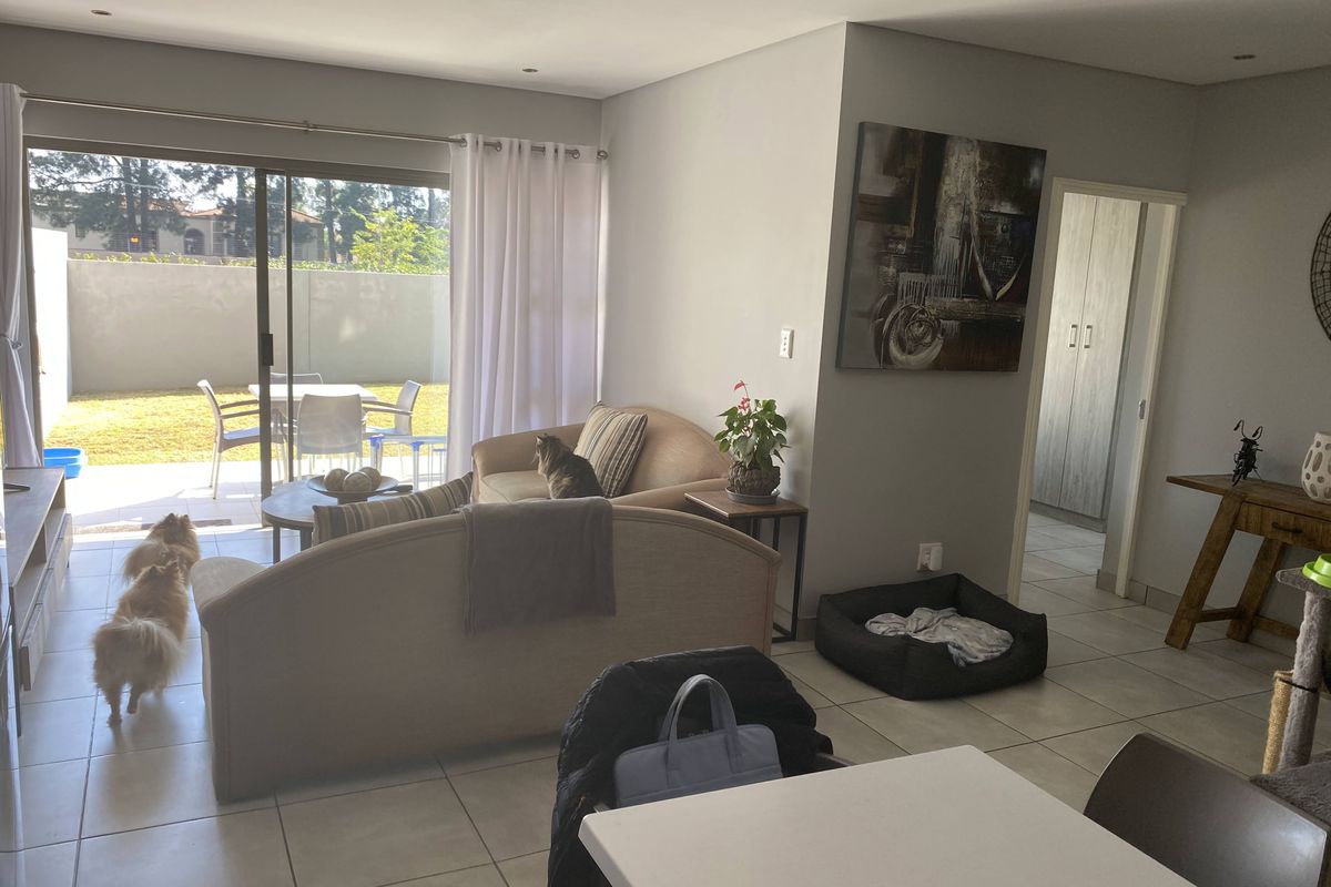 Open-plan living area featuring tiled floors, recessed lighting, and large sliding glass doors providing direct access to the outdoor patio and garden.