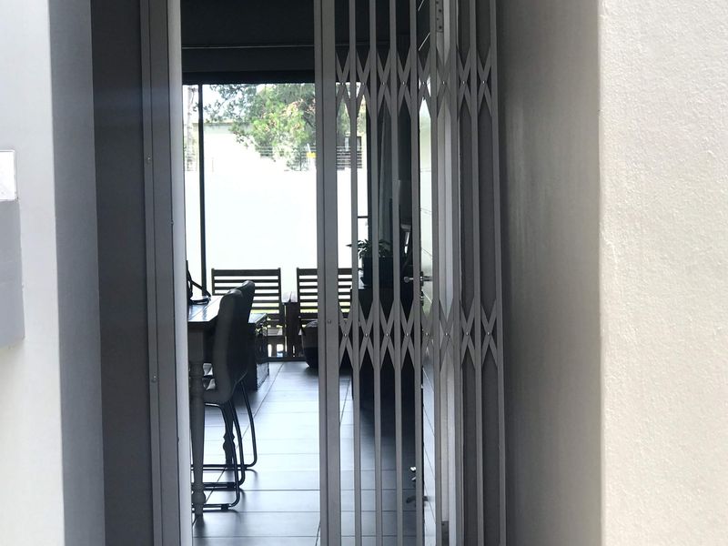 Entrance area featuring a secure metal security gate and tiled flooring, providing access into the main living space of the apartment.