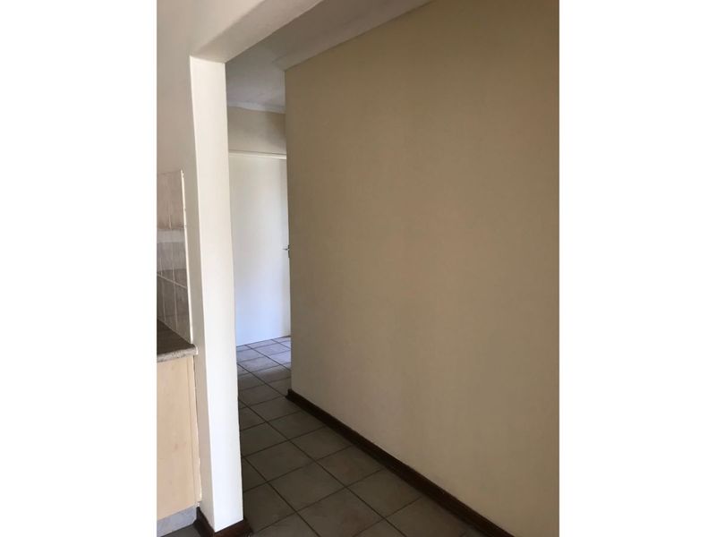 A simple, empty hallway featuring tiled flooring and neutral wall finishes, providing a clean transition between living spaces.